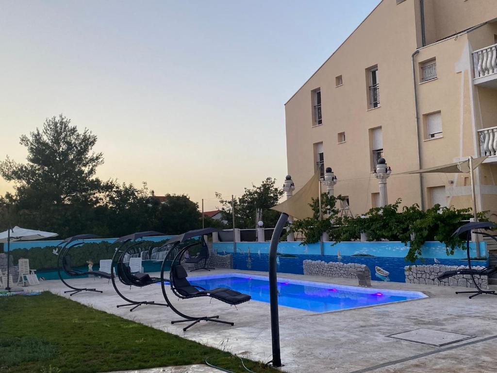 einen Spielplatz vor einem Gebäude mit Pool in der Unterkunft Apartmani Ivan V RELAX in Vodice