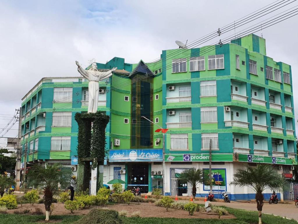 un edificio verde con una statua davanti di Hotel El Cristo a Cobija