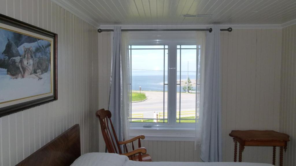 a bedroom with a window with a view of the ocean at La Maison entre Mer Montagnes in Cap-Chat
