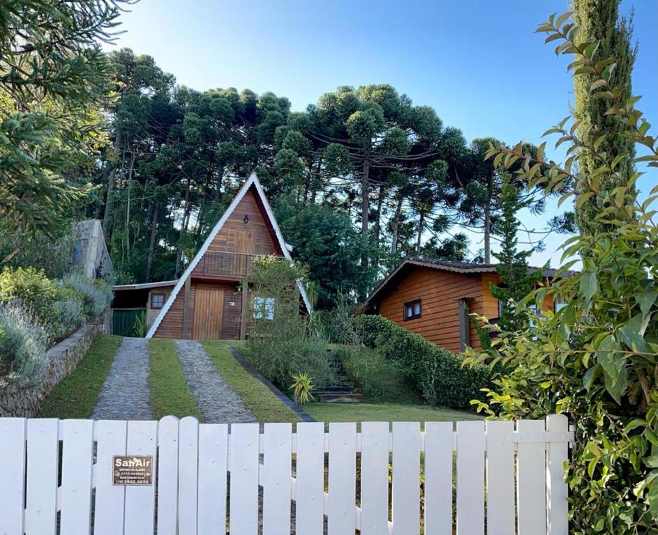 a white fence in front of a wooden house at Chalé Gran Reserva in Monte Verde