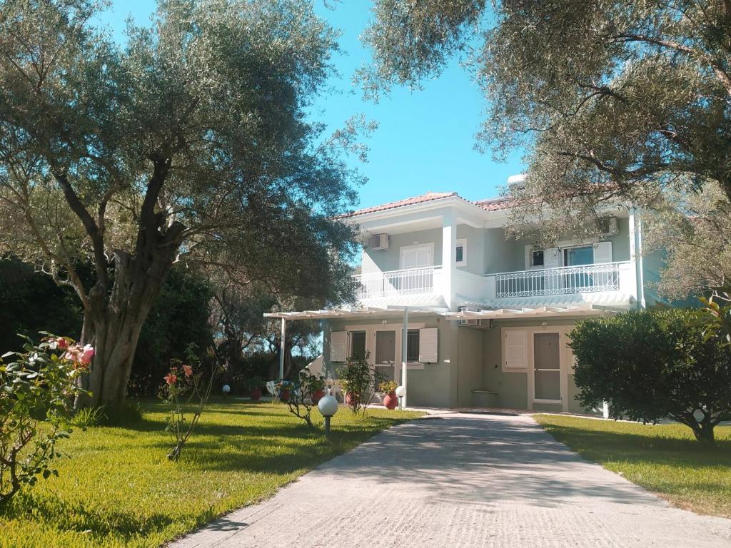 una casa blanca con un árbol y una entrada en ELAIA - Apartments & Studios, en Lefkada