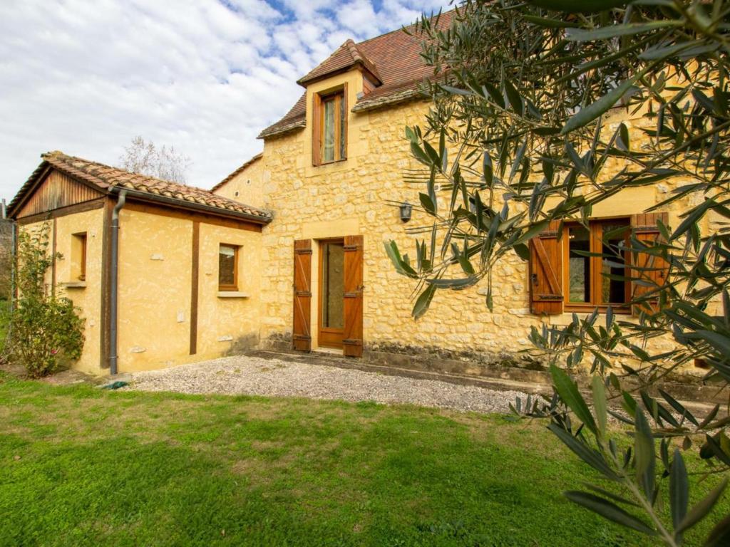 une grande maison en pierre avec une cour herbeuse dans l'établissement Gîte La Roque-Gageac, 3 pièces, 4 personnes - FR-1-616-153, à La Roque-Gageac