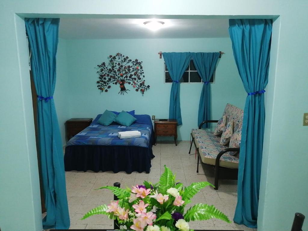 - une chambre avec des murs bleus, un lit et un canapé dans l'établissement DEPARTAMENTO CERCANO AL AEROPUERTO T2, A 2 CALLES, à Mexico