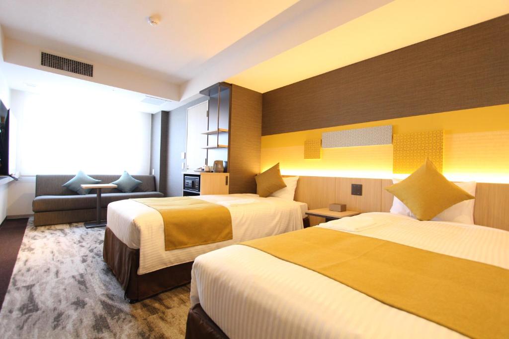 東京にあるKOKO HOTEL Tsukiji Ginzaのベッド2台とソファがあるホテルの部屋