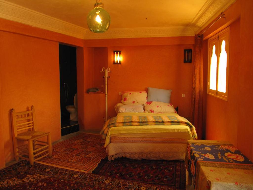 um quarto com paredes cor de laranja, uma cama e uma janela em Auberge Cavaliers em Aït Baha