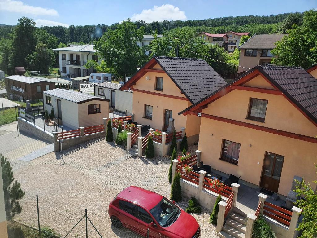 een rode auto geparkeerd op een parkeerplaats naast de huizen bij Bungalows Michalka - Podhájska in Podhájska