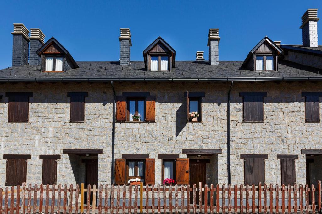 un antiguo edificio de piedra con ventanas y una valla en Torres de Vallibierna, en Benasque