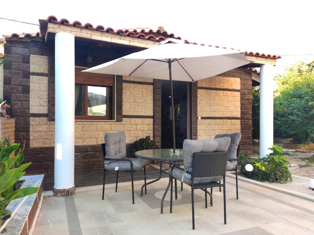 a patio with a table and chairs and an umbrella at La casa di Tsabika in Koskinou