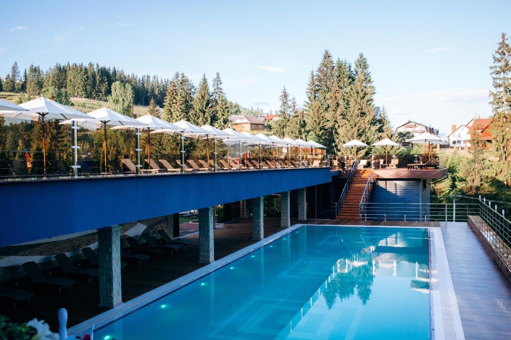 una piscina en un hotel con sillas y sombrillas en GasthauS & SPA en Bukovel