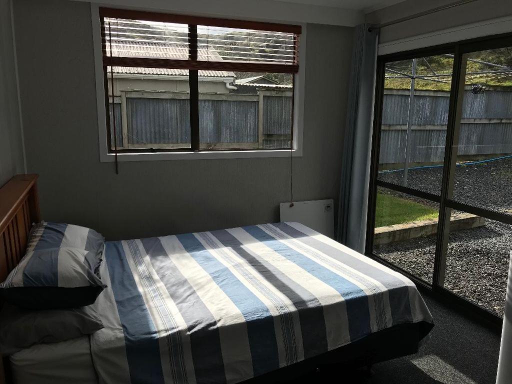 a bedroom with a bed with a striped blanket and a window at Kiwi Cabins in Tapu