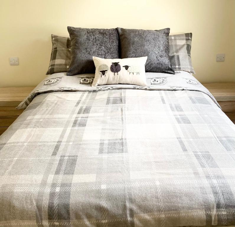 a bed with a gray and white plaid blanket at Stiles of Ambleside in Ambleside