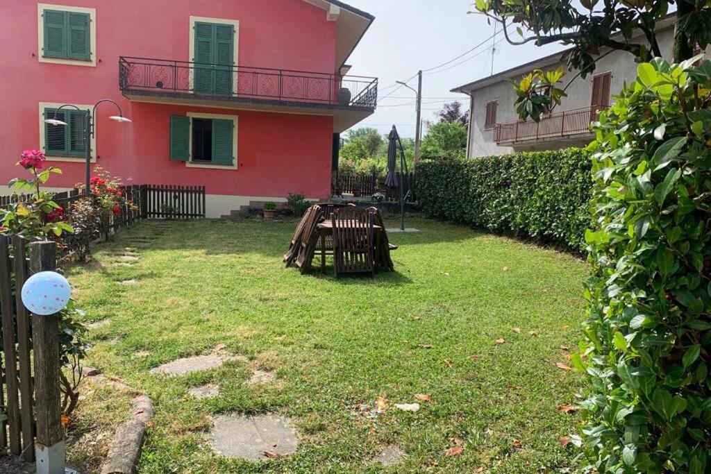 einen Hof vor einem rosa Haus mit einem Tisch in der Unterkunft Appartamento nel verde tra Cinque Terre e Versilia in Barbarasco