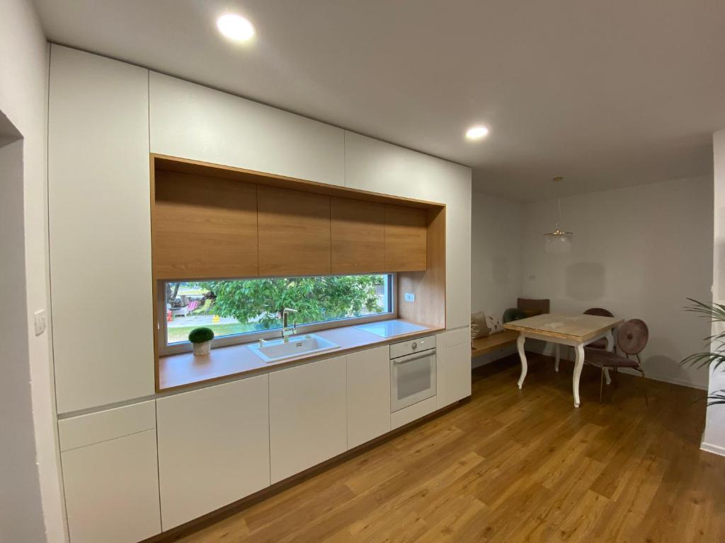 cocina con armarios blancos, fregadero y ventana en Apartma pri nani, en Kobarid