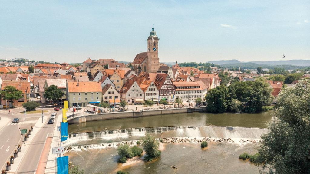 a city with a river in front of a town at Das Hölderlein - Altstadthotel in Nürtingen