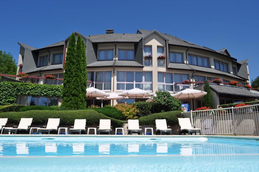 un hotel con una piscina con sillas y sombrillas en Bastide du Cantal en Salers