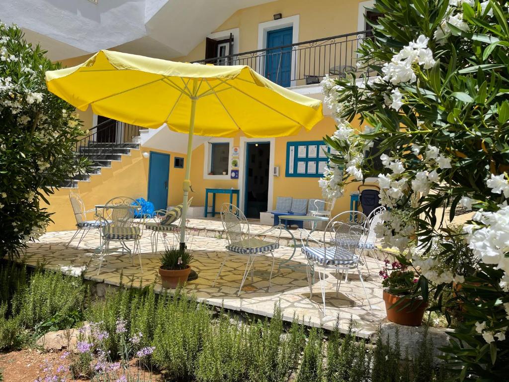 un patio con sombrilla amarilla, sillas y mesas en Sunflower Apartments & Studios, en Kassiopi