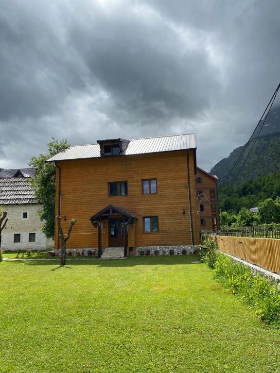 una gran casa de madera con un patio de césped en Guesthouse Mehmeti, en Valbonë