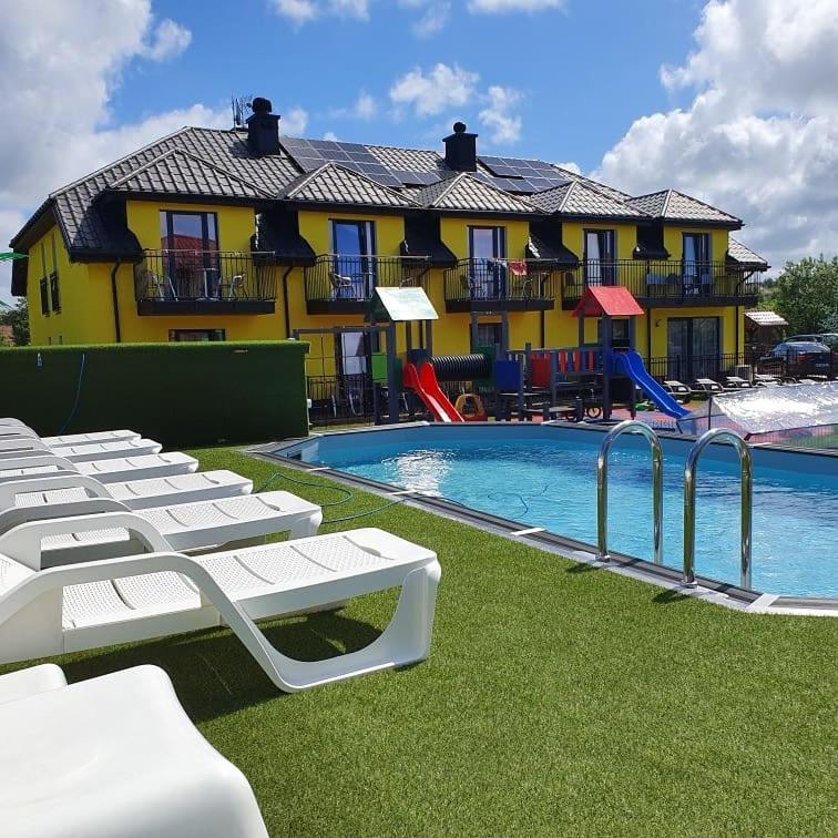 a swimming pool with lounge chairs and a building at Willa Kwiatano - Plac zabaw & Jacuzzi & Basen & Sauna - Budynek C in Grzybowo