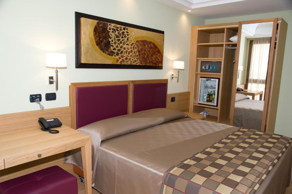 a bedroom with a bed and a desk with a phone at Artemis Hotel in Cefalù