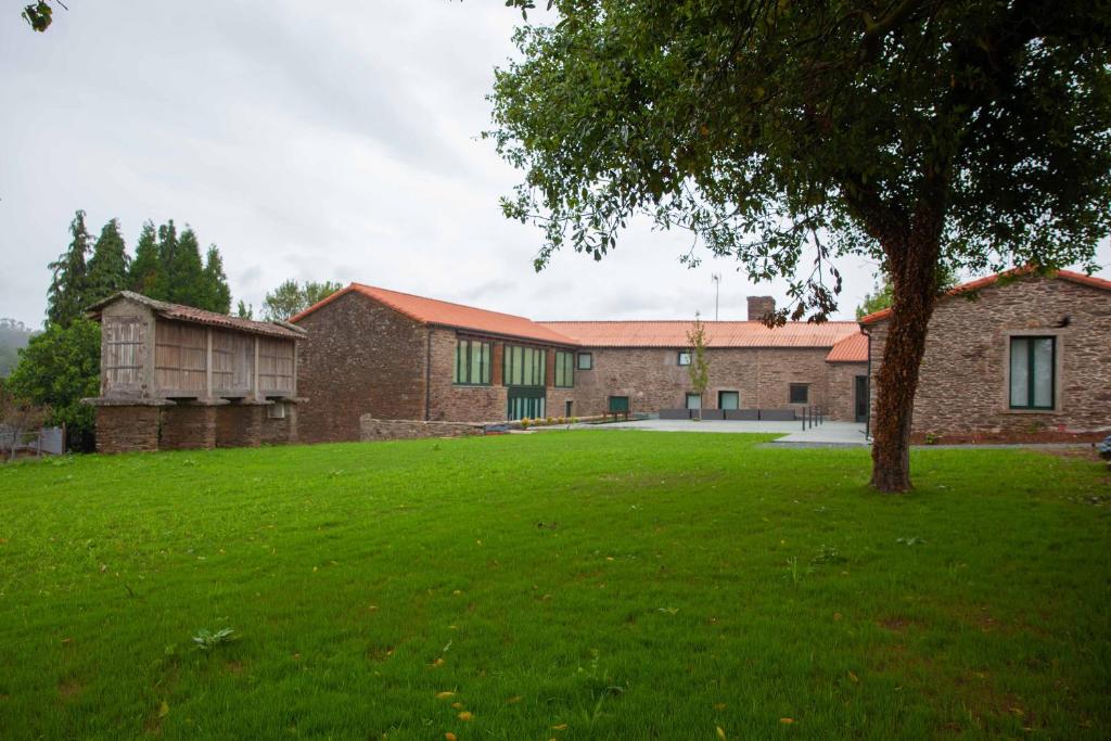 a brick building with a tree in a yard at Casa Rico de Medín in O Pino 