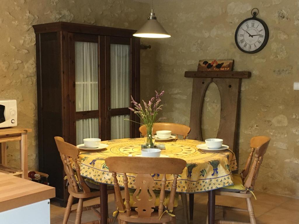 a dining room table with chairs and a clock on the wall at L&#39;Olivier in Puisseguin