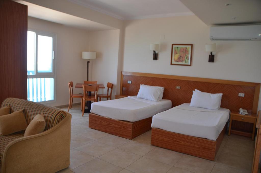 a hotel room with two beds and a couch at Negresco Hotel in Marsa Matruh