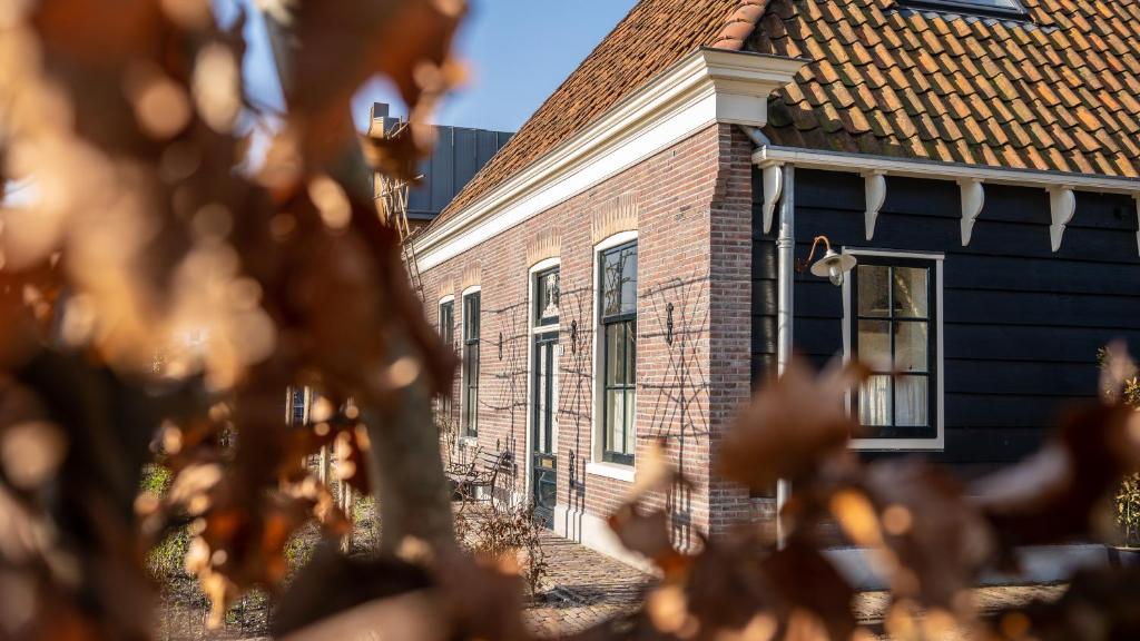 a brick house with a brown roof at Traditional family apartment with garden at countryside Amsterdam in Landsmeer