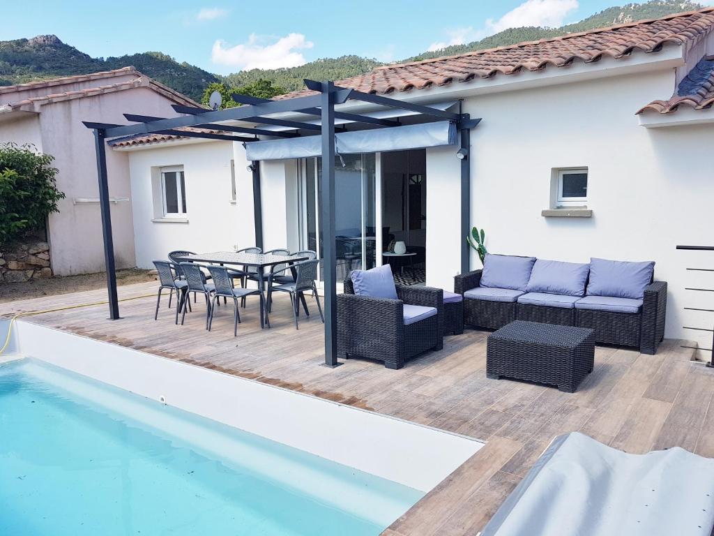 a patio with a table and chairs next to a pool at SANTA LUCIA in Sainte-Lucie de Porto-Vecchio