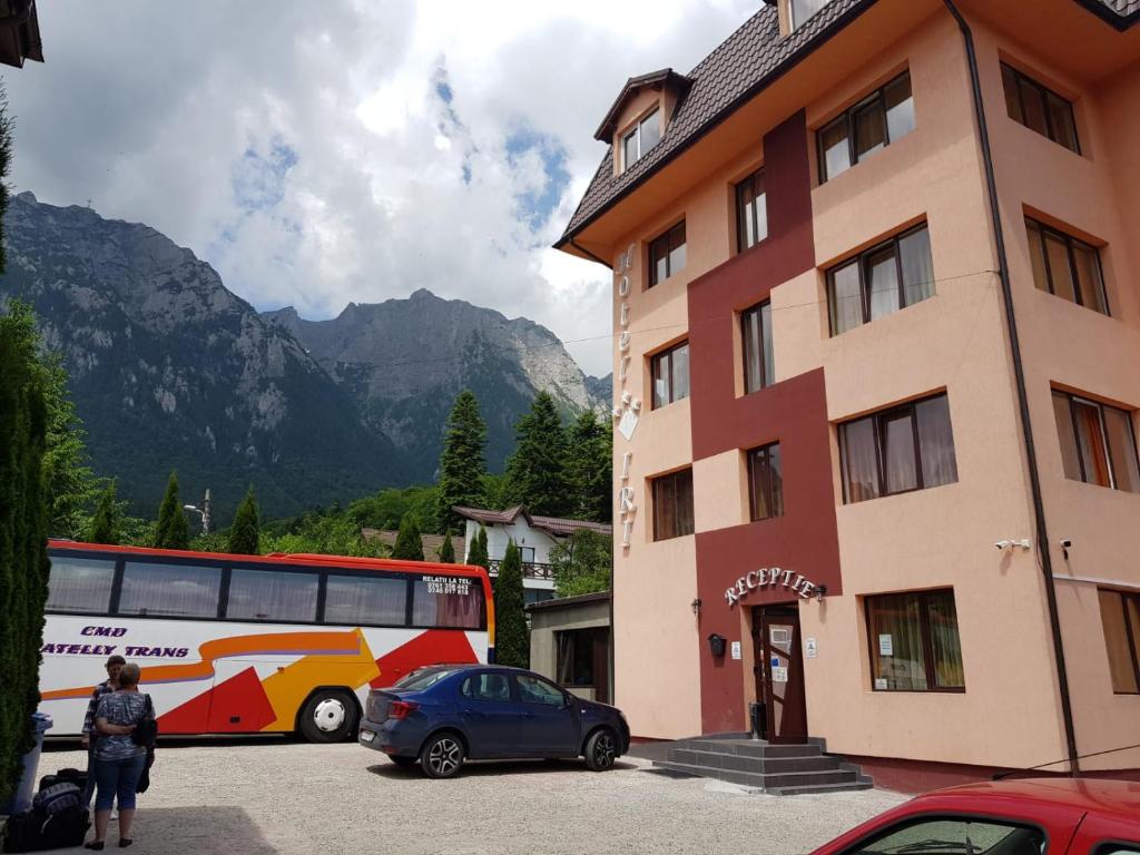 een bus geparkeerd op een parkeerplaats naast een gebouw bij Hotel Iri in Buşteni