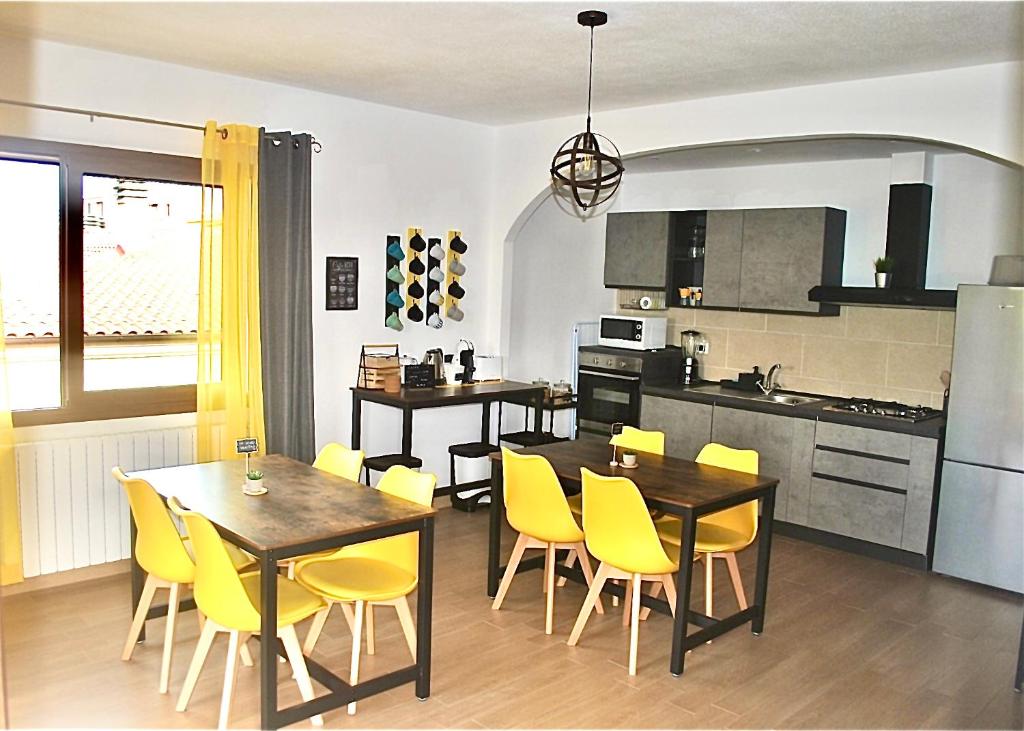 Verba Mundi Guest House في أولبيا: مطبخ وغرفة طعام مع كراسي وطاولات صفراء