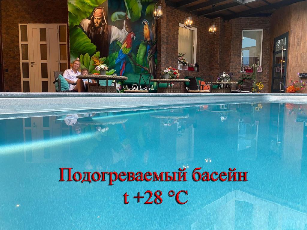 una gran piscina con una mujer sentada al lado de una pintura en Hotel Nika, en Adler