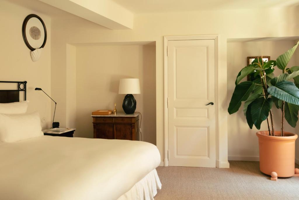 a bedroom with a white bed and a potted plant at Hotel la Ponche in Saint-Tropez
