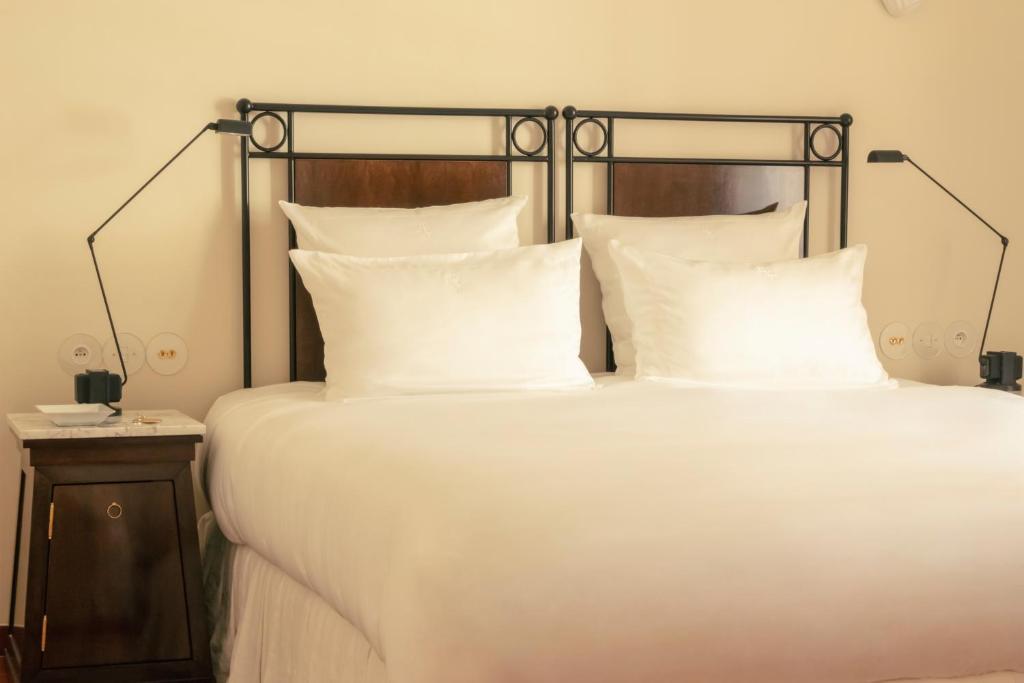 a bed with white pillows and a black frame at Hotel la Ponche in Saint-Tropez