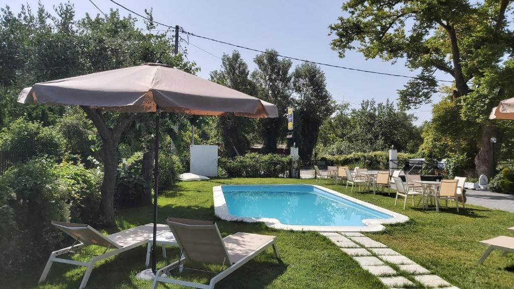 a swimming pool with an umbrella and chairs and a table at Stelios House in Asprovalta