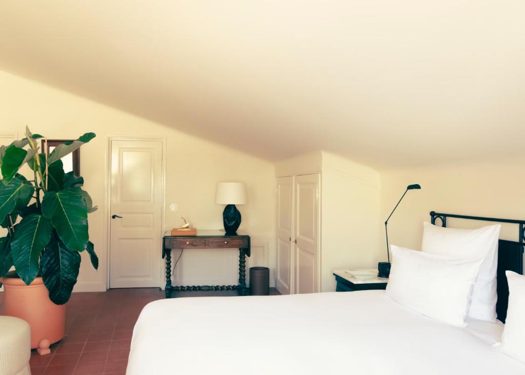 a bedroom with a white bed and a plant at Hotel la Ponche in Saint-Tropez