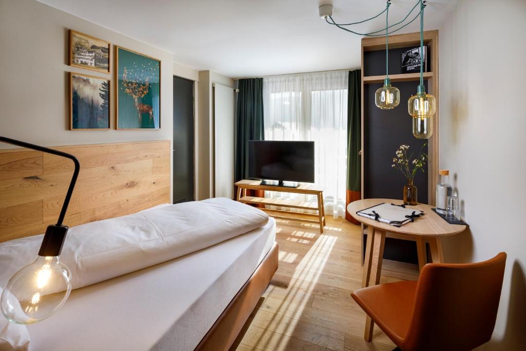 een hotelkamer met een bed, een tafel en een televisie bij Hotel Hirschen Wildhaus in Wildhaus