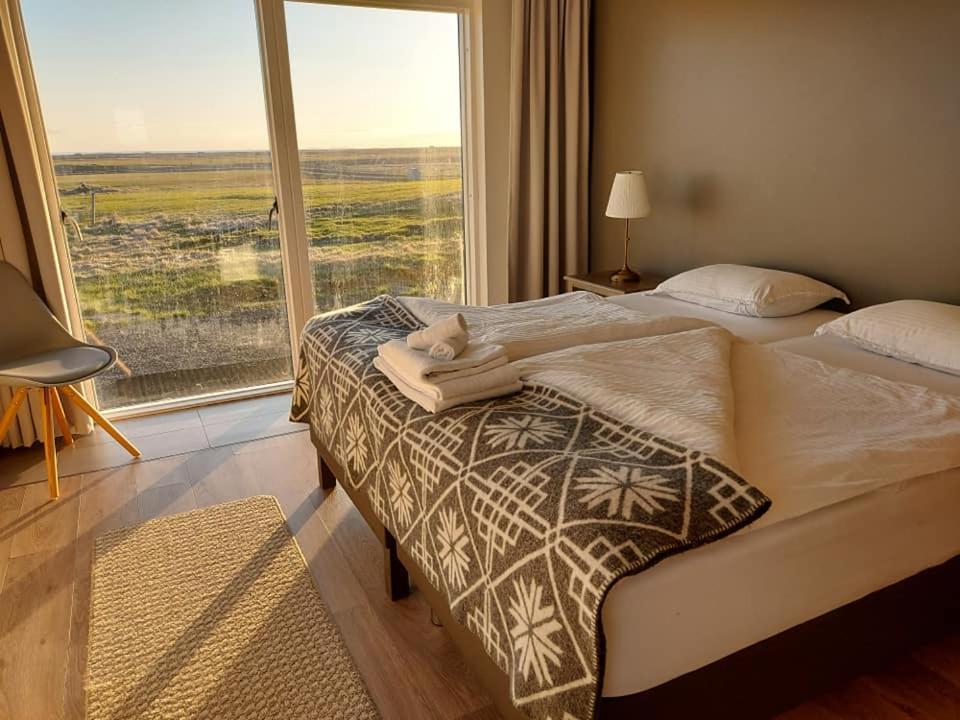 una camera da letto con un letto e una grande finestra di Farmhouse Lodge a Vík