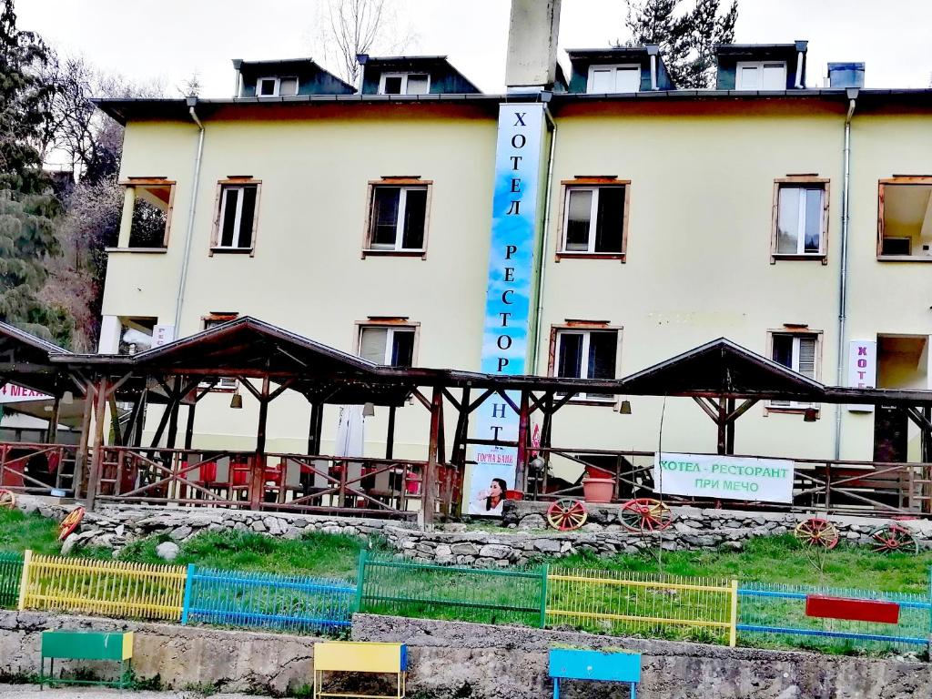 a large white building with black umbrellas in front of it at Семеен Хотел "При Мечо" in Rilski Manastir