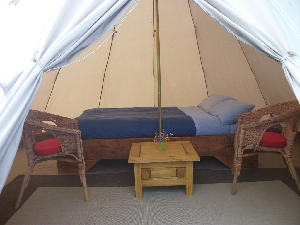 a bed in a tent with two chairs and a table at Aille River Tourist Hostel Glamping Doolin in Doolin