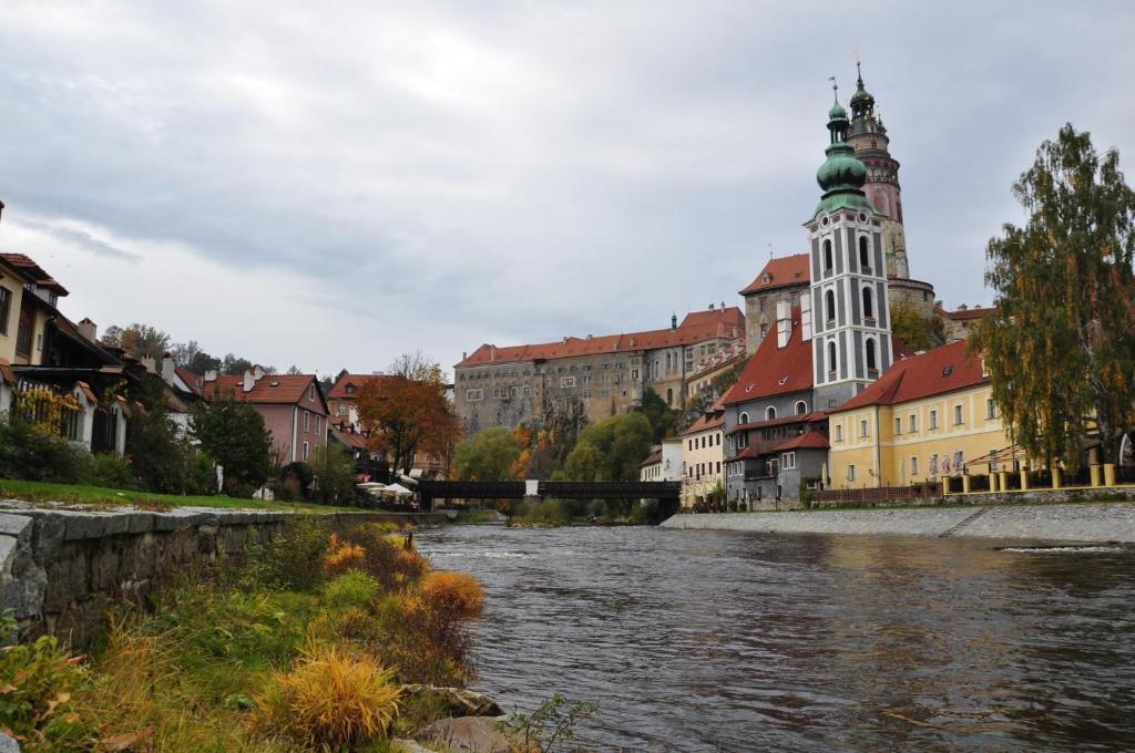 a river in a city with buildings and a church at Guest House Olšakovský in Český Krumlov