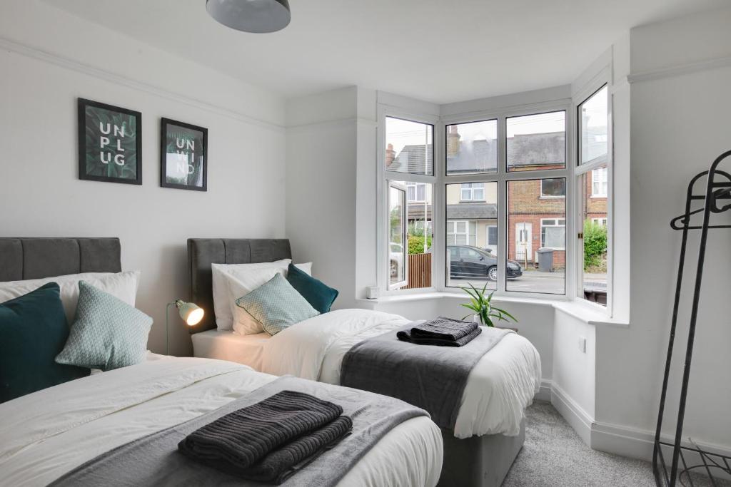 1 dormitorio con 2 camas y ventana en Spacious, Modern Three Bed House - Free Parking & Wifi, en Chelmsford