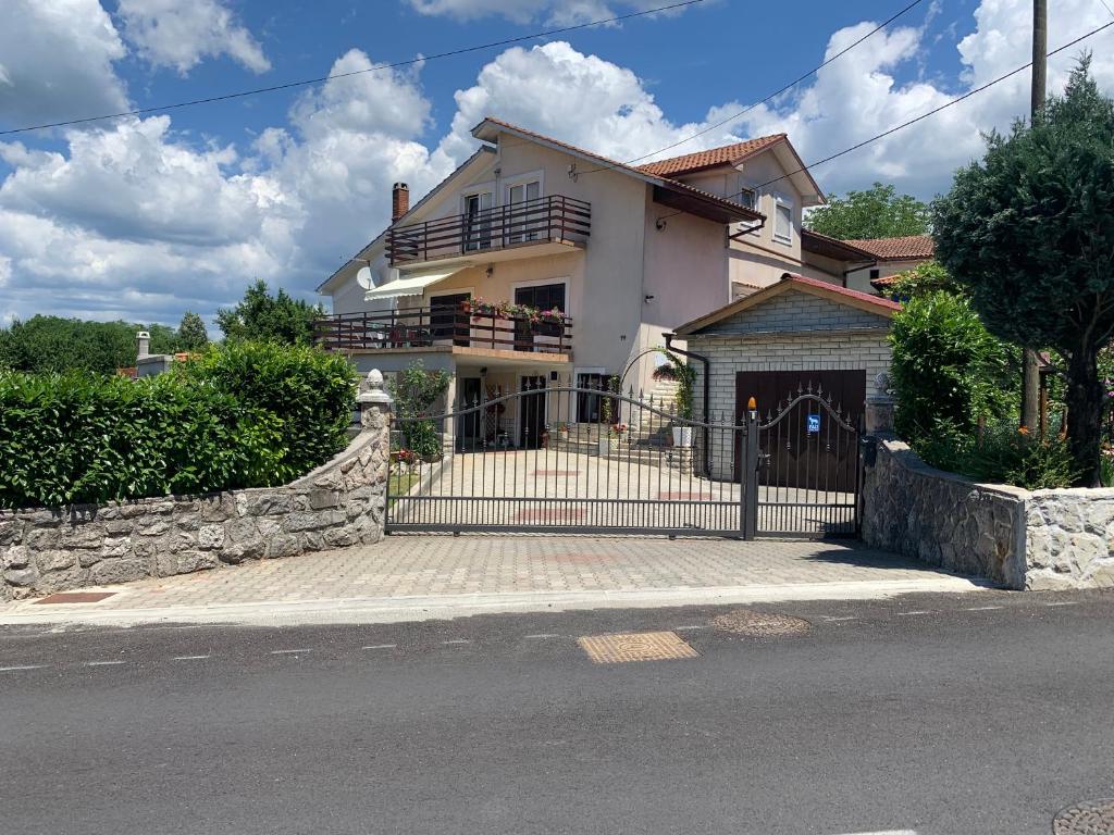 a white house with a gate on a street at Lovre in Viskovo