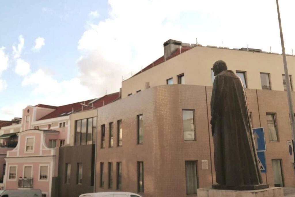 une statue d'un homme debout devant un bâtiment dans l'établissement Bairro da Apresentação no coração de Aveiro, à Aveiro