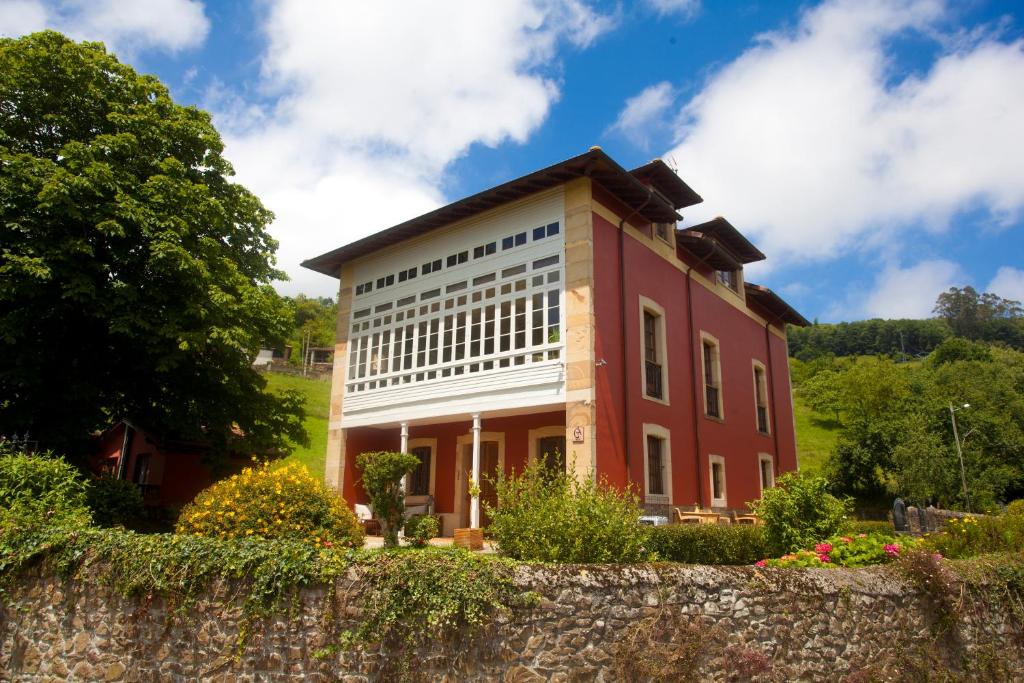 um grande edifício vermelho com uma parede de pedra em Casona de Indias em Piloña