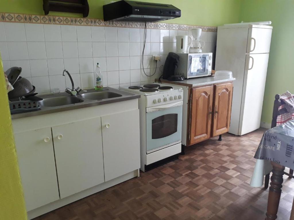 a kitchen with a stove and a sink and a refrigerator at Chambre familliale in Questembert