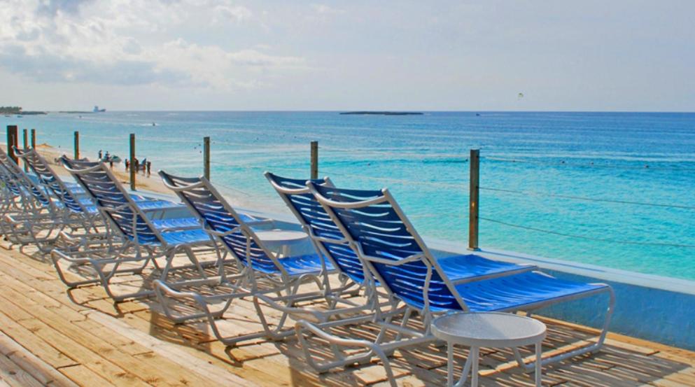 una fila de sillas azules sentadas en la playa en Paradise Island Beach Club Ocean View Villas en Creek Village