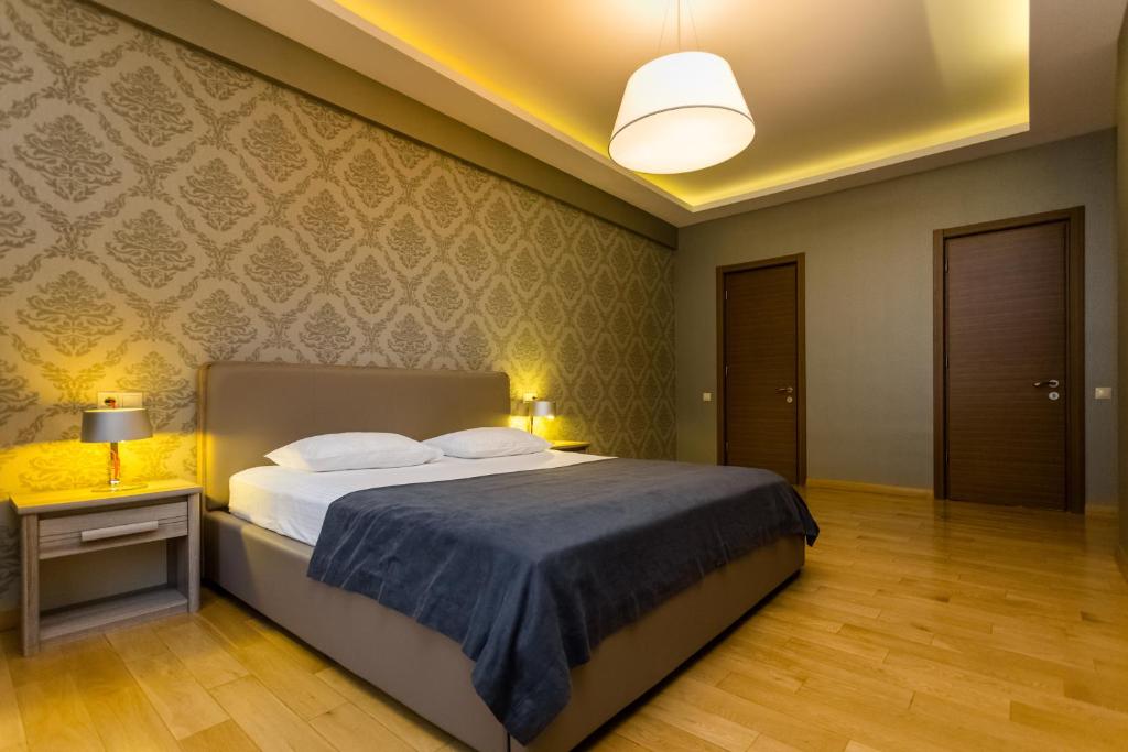 ein Schlafzimmer mit einem Bett mit einer blauen Decke und einer Lampe in der Unterkunft Premium 2 Bedroom Apartment in Tbilisi City