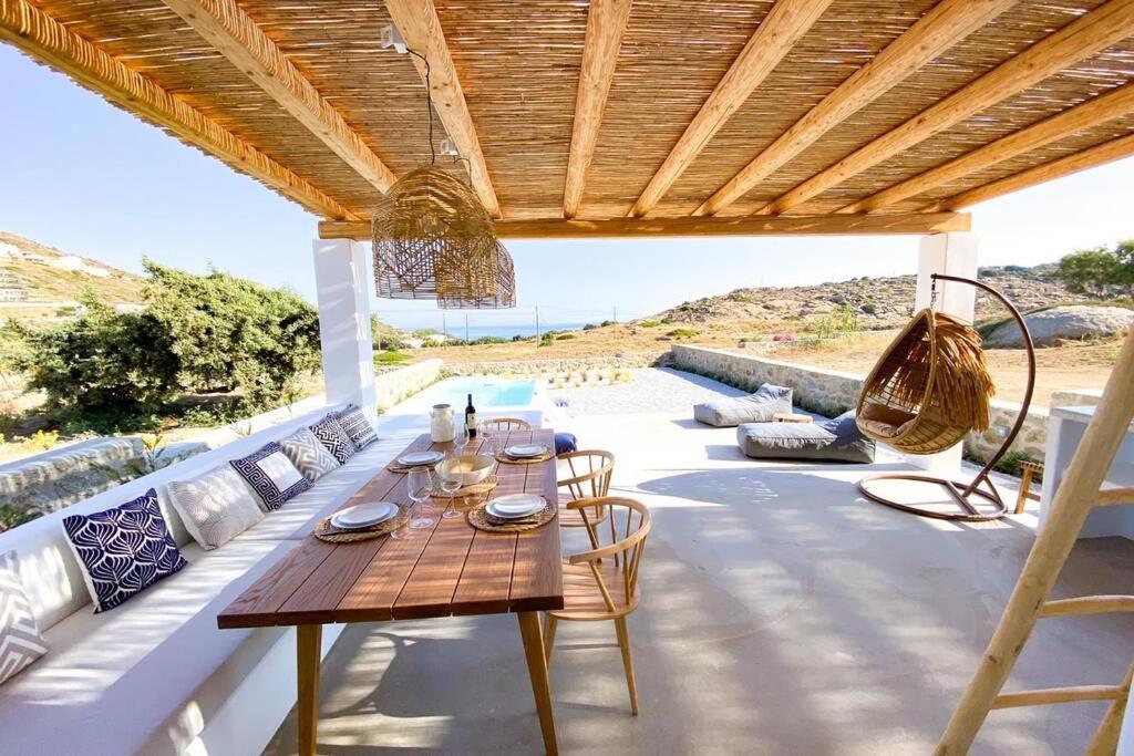 eine Terrasse mit einem Tisch und Stühlen unter einem Holzdach in der Unterkunft Luxury Cycladic Villa with Seaview and MiniPool in Naxos Chora