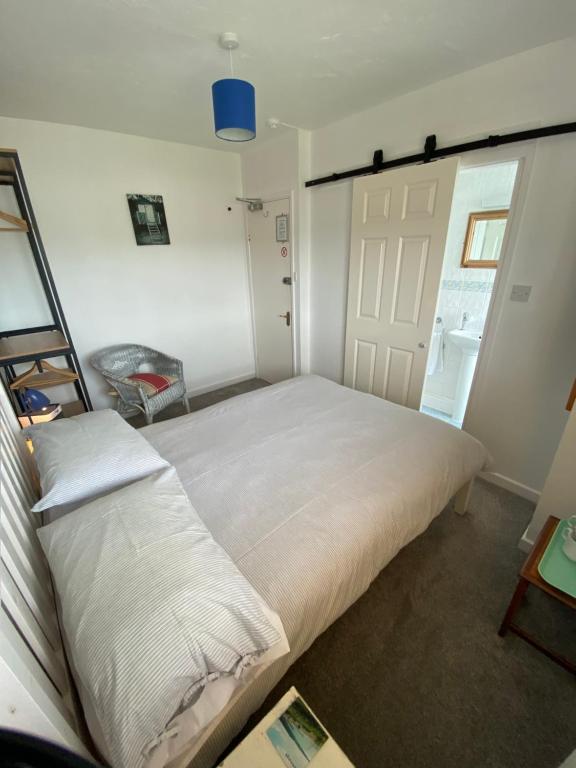 a bedroom with a large white bed and a door at The Sandhaven in Swanage
