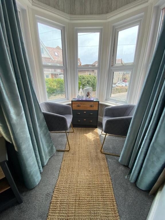 a living room with two chairs and two windows at The Sandhaven in Swanage